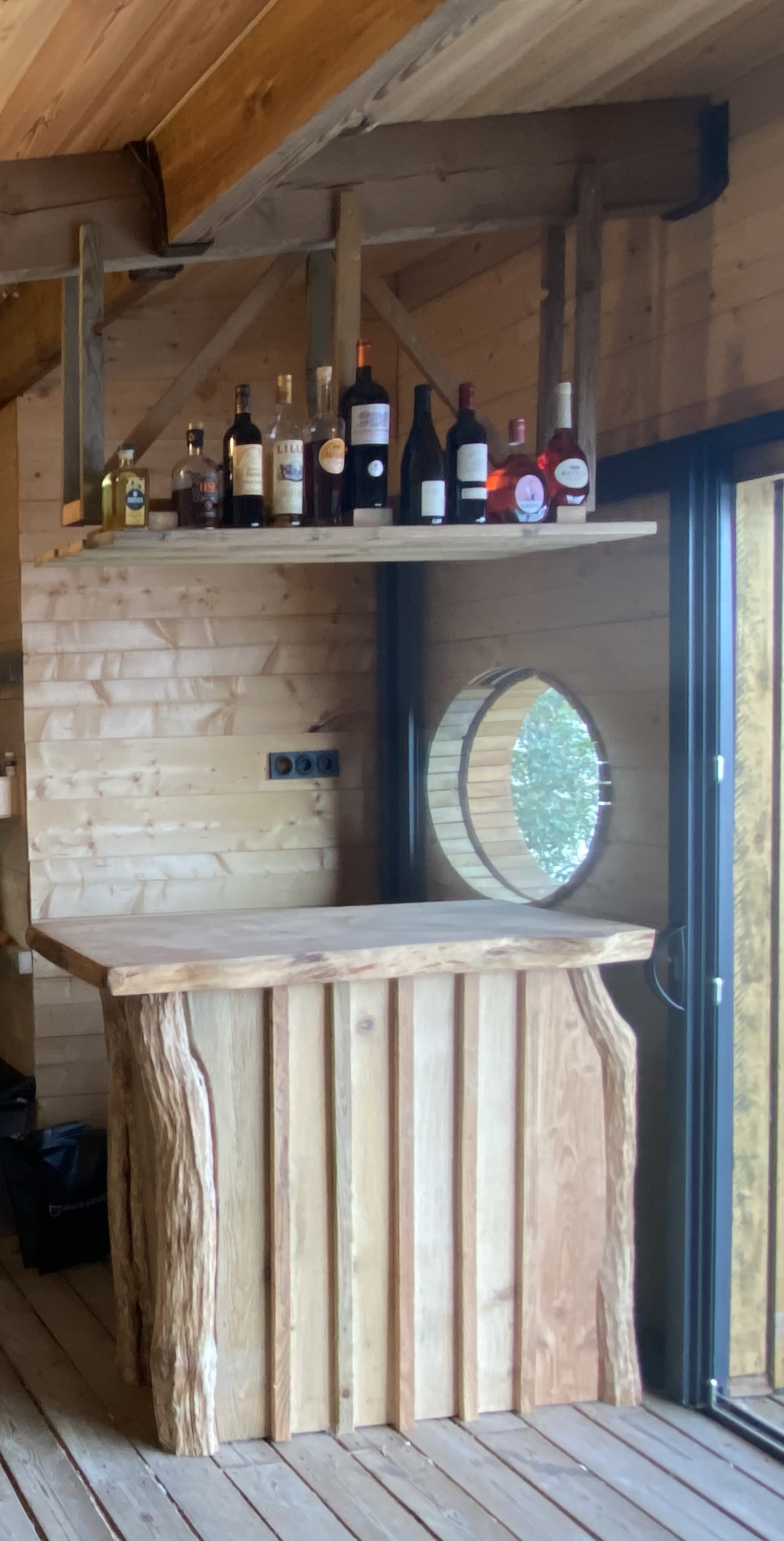 Intérieur de la cabane : poêle à bois en fonte, coin cuisine et bar