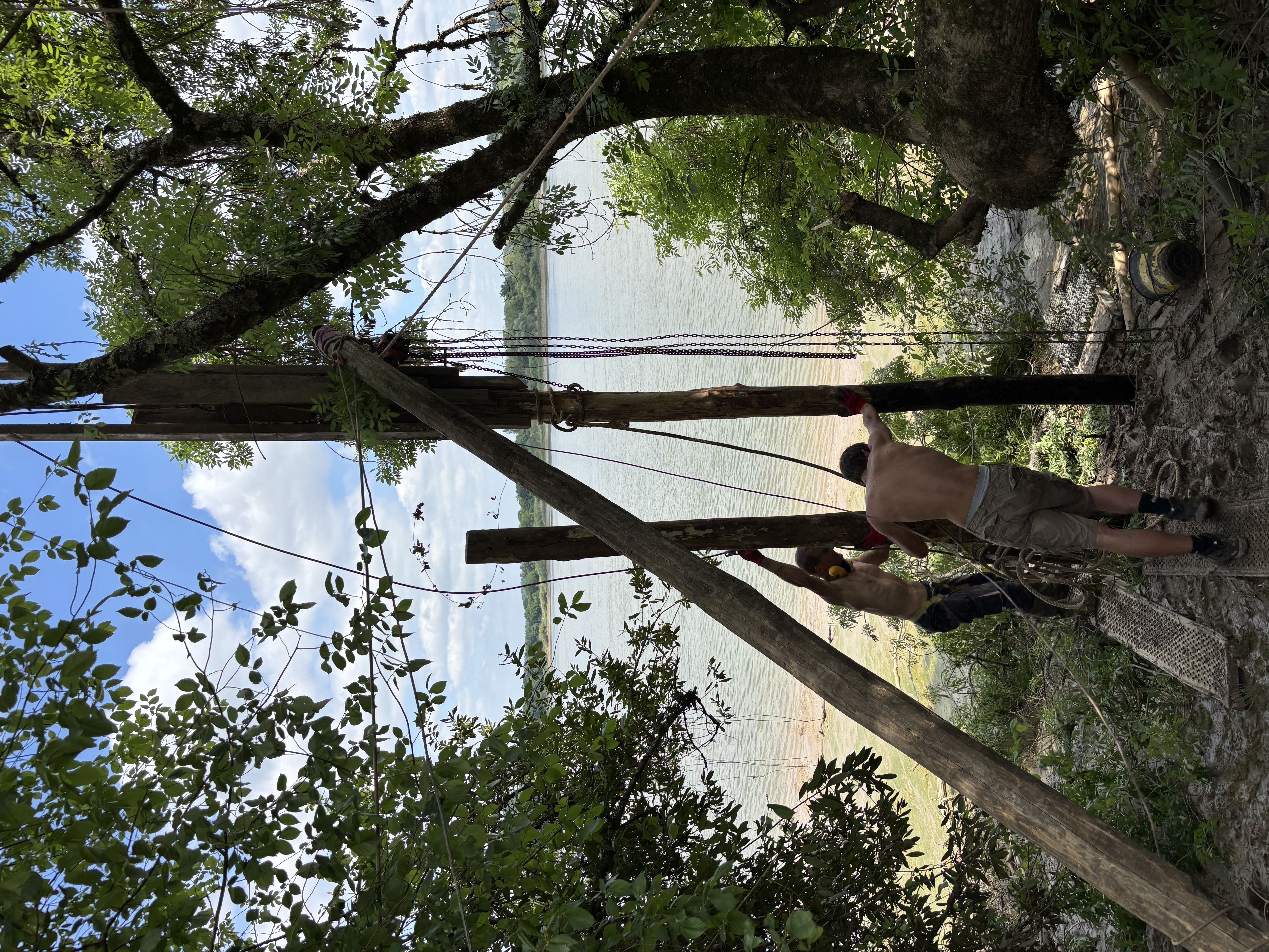 Pose des pieux du carrelet en eau : ouvrier sur échelle assemblant une pièce de bois sur un pieu